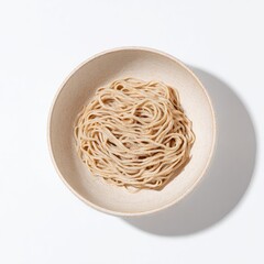 A beige bowl holds a nest of light brown, thin noodles against a bright white background, cast with a subtle shadow