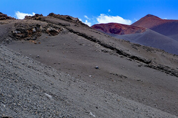 Volcanic ash slopes with rugged textures and red crater ridges under a vivid blue sky, a breathtaking geological landscape showcasing the power of nature, ideal for adventure travel, trekking, and vol