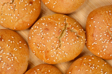 A full-frame, close-up shot capturing a group of fresh, golden-brown homemade sesame seed buns