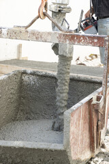 Pouring fresh ready-mixed concrete from mixer into a wheelbarrow during for construction