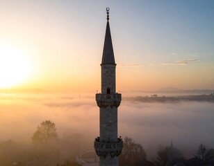 Mosque minaret at sunrise through fog