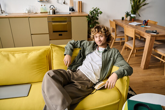 Relaxing moment of a stylish man in casual wear on a cozy yellow sofa at home