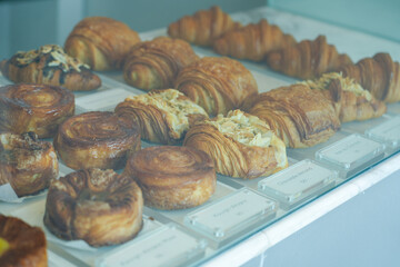 Shot of different pastries on display in a cafe showcase. Croissants, cinnamon rolls, pretzels. Fresh homemade baked goods include croissants and breads and fresh butter.