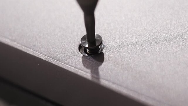 close up. screwdriver and screw. A technician disassembles a laptop.