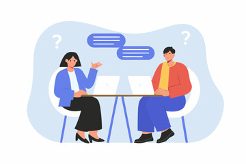 Two people sitting at a table with laptops discussing and asking questions