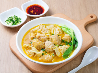 Chinese dumplings served with a small bowl of condiments, including scallions and chili sauce