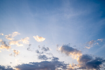 White fluffy clouds float gently in a clear blue sky on a bright sunny day. The scene feels open clean and refreshing.