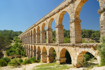 Obraz premium Ancient Roman aqueduct, the Pont del Diablespanning the Barranc del Diable near Tarragona, perfect for historical travel content and heritage promotions.