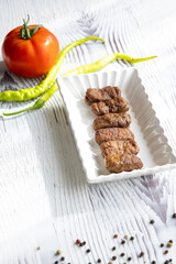 Close-Up of Romanian Mici Sausages Served with Flatbread and Tomatoes on a White Plate
