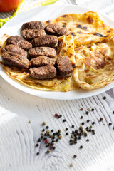 Close-Up of Romanian Mici Sausages Served with Flatbread and Tomatoes on a White Plate
