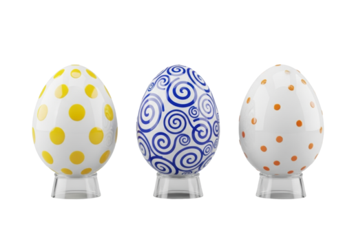 Three porcelain Easter eggs (yellow polka dots, blue swirls, orange confetti) on acrylic stands, isolated on transparent background, high-angle commercial product display