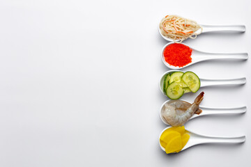 Sushi ingredients in white spoons on a white background. Shrimp, mango, cream cheese