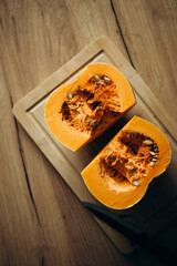 Orange ripe pumpkin cutted into two halves on a wooden table.