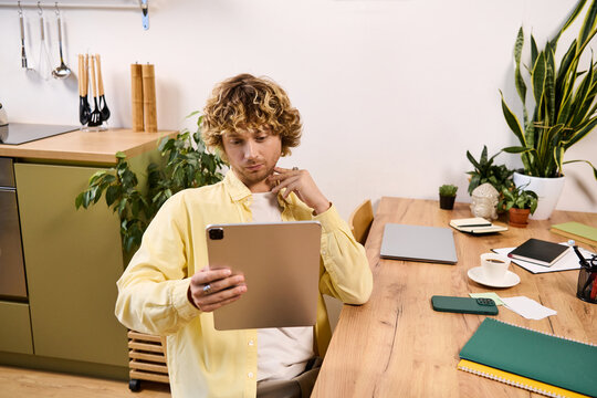 Casually dressed man enjoying time at home while using a tablet in a cozy kitchen
