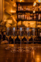 Four elegant champagne glasses are meticulously lined up on a bar