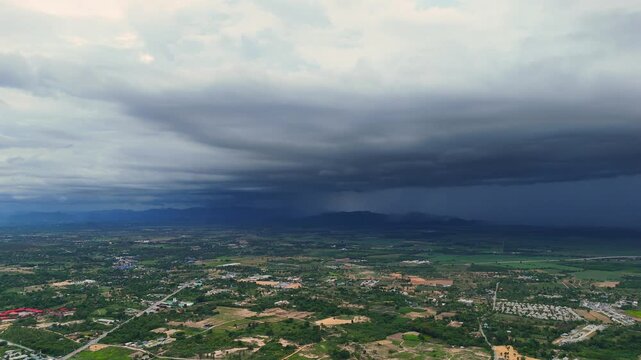 Rainfront expands across farmland under dramatic sky during tropical storm in Thailand