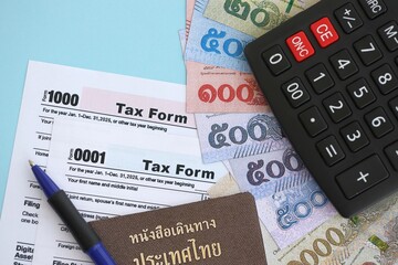 Thai baht money bills and calculator with tax form on blue. Taxation and accounting concept