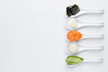 White spoons with sushi ingredients - salmon, cream cheese, isolated on a white background