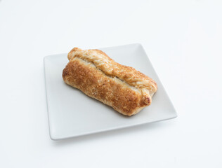 Freshly baked puff pastry roll on a white plate.