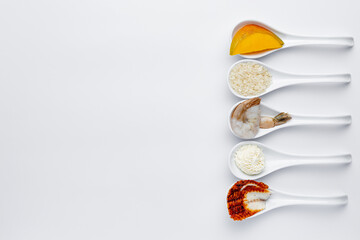 Sushi ingredients in white spoons on a white background. Shrimp, mango, cream cheese
