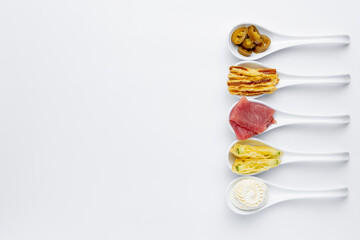 Sushi ingredients in white spoons on a white background. Tuna, mango, cream cheese
