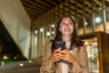 Young woman smiling using smartphone at night