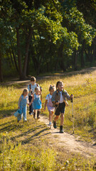 Fototapeta premium Group of children hiking together in forest path with adventure spirit. Concept of childhood friendship, outdoor activities, tourism, family lifestyle, and education.