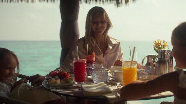Mother and children enjoying a luxury breakfast at an overwater villa on an island resort