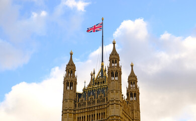 Obraz premium British national flag waving on building of the Palace of Westminster (Houses of Parliament) in London. Flag of Great Britain is one of state symbols of state of Great Britain and Northern Ireland.