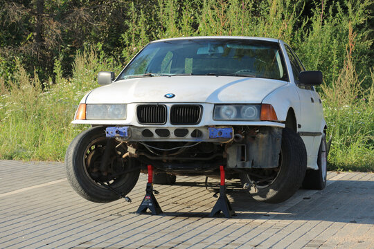  Car repair and maintenance. A damaged white BMW, missing its front bumper, raised on two jacks. Minsk, Belarus, August 21, 2025