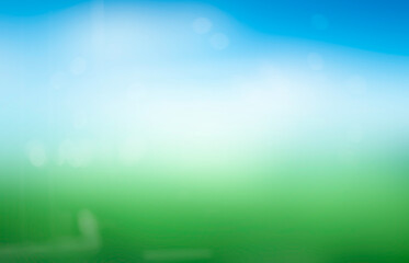 Abstract blur nature background with green grass and blue sky with white clouds.