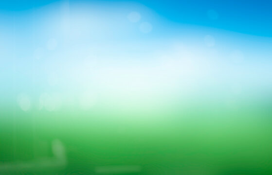 Abstract blur nature background with green grass and blue sky with white clouds.