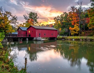 Obraz premium Autumnal sunrise over a red covered bridge reflecting on calm water