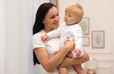 Smiling mother hugging her cute baby at home