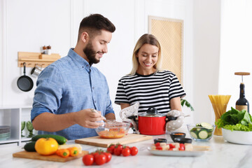 Happy couple cooking together at table in kitchen