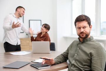 Obraz premium Man feeling jealous of his colleague's success in office, selective focus