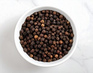 Black peppercorns in a white bowl on a marble surface
