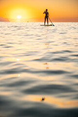 Serene woman paddleboarding in ocean at sunset