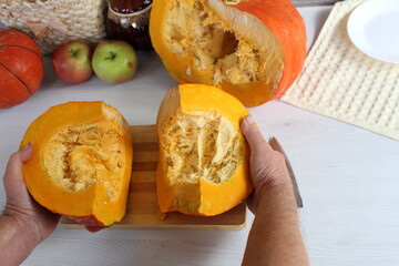 A woman in the kitchen is peeling a pumpkin to cook something delicious.