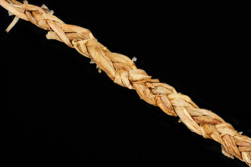 A close-up shot of a rustic, hand-braided strand of dried natural fibers, laid diagonally on a solid dark background