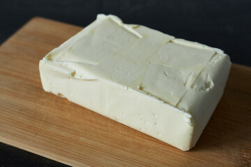 Butter on a wooden cutting board on a black background.