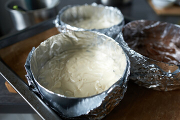 A close-up of a baking sheet with dough on the kitchen counter. Making sponge cake layers.