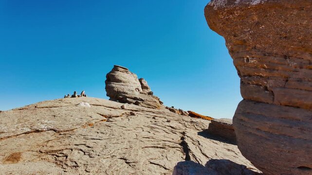 Mushroom shaped and anthropomorphic rock formations in a beautiful mountain range, displaying weathered stone columns, rounded caps, and curious silhouettes, under open sky across rugged terrain