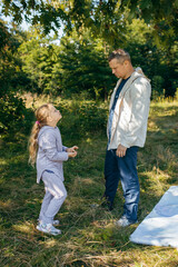 Fototapeta premium Adult father and little daughter are walking in the park