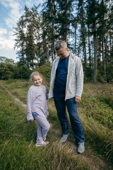 Fototapeta premium Adult father and little daughter are walking in the park