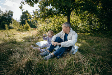 Fototapeta premium Adult father and little daughter are walking in the park