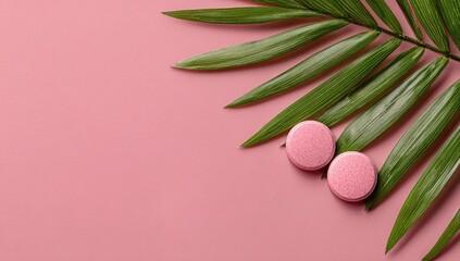 Two pink tablets rest beside a palm leaf on a pink background