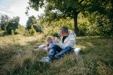 Fototapeta premium Adult father and little daughter are walking in the park