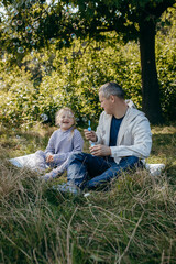 Adult father and little daughter are walking in the park