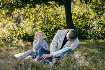 Adult father and little daughter are walking in the park